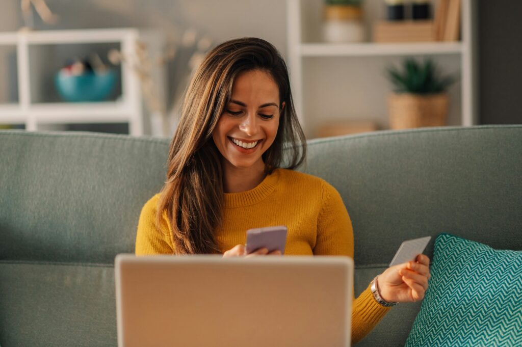 Woman buying online on a laptop at home and using a smartphone